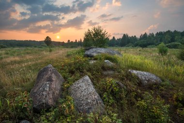 Taşlarla çayırda gün batımı