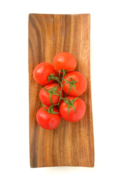 Branch of ripe tomatoes on a wooden plate — Stock Photo, Image