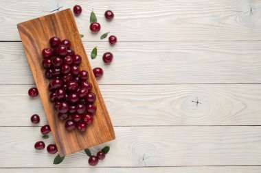 olgun kiraz ve ahşap bir tabakta yaprakları