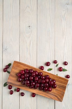 olgun kiraz ve ahşap bir tabakta yaprakları