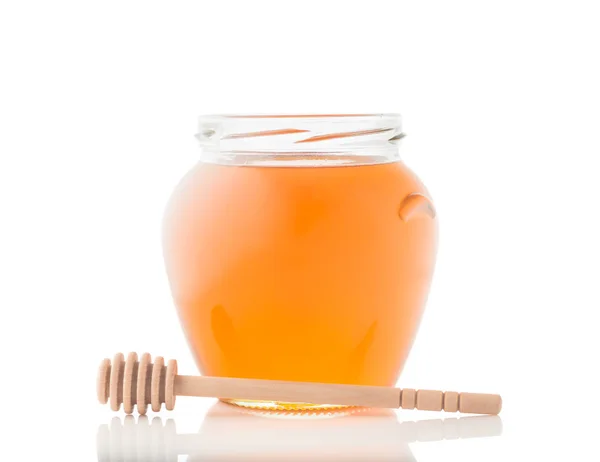 Glas voll Honig und Holzstäbchen drauf — Stockfoto