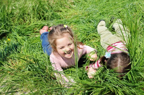 姉妹の女の子は草の中で遊ぶ — ストック写真
