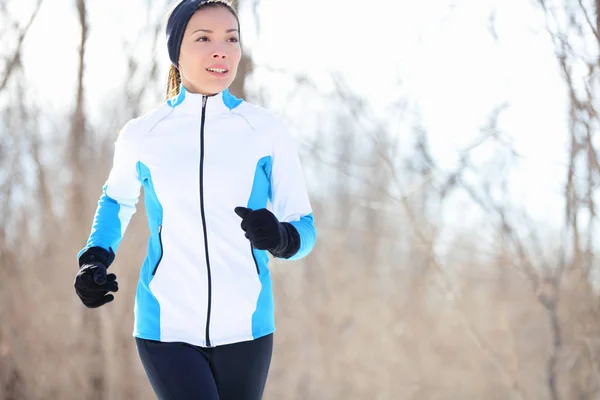 Running young Asian woman jogging in a winter fleece and gloves in open countryside with copyspace in a health and fitness concept