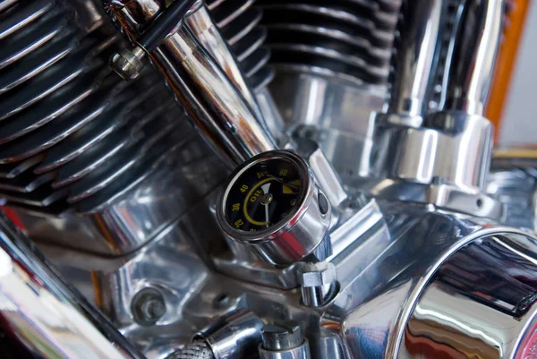 Oil pressure gauge on chrome, V2 motorcycle engine. Shallow depth of field with only the gauge in focus.