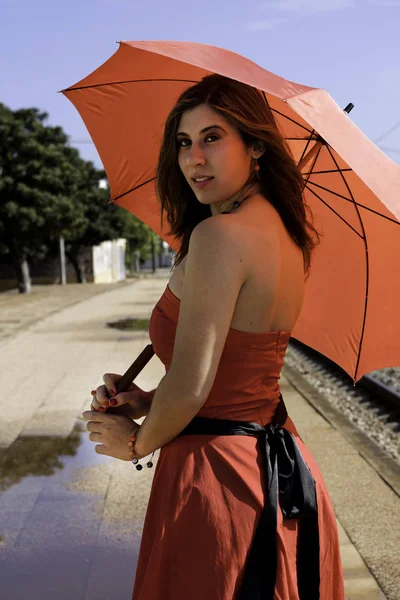 鉄道駅に赤いドレスと傘を持つ美しい女性のビュー — ストック写真