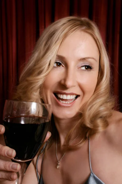 Happy female holding a glass of red wine