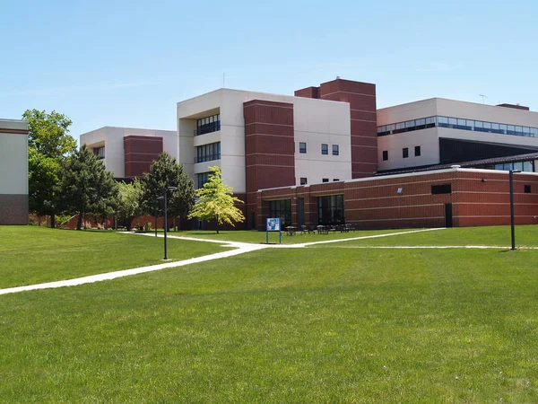 an exterior view of a college building with a large grass area in front of it