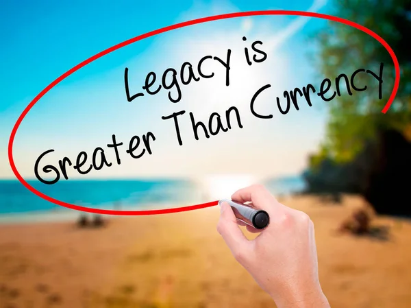 Man Hand writing Legacy is Greater Than Currency with black marker on visual screen. Isolated on background. Business, technology, internet concept. Stock Photo