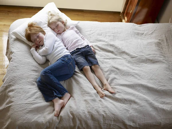 Duas Irmãs Mentem Dormindo Uma Cama Vista Elevada — Fotografia de Stock