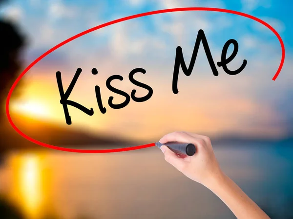 Women Hand writing Kiss Me with black marker on visual screen. Isolated on Sunset. Business, technology, internet concept. Stock Photo