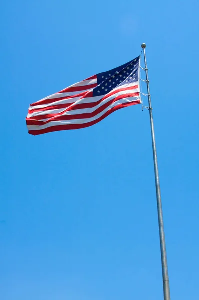 Μια Αμερικάνικη Σημαία Φυσάει Στον Άνεμο Μπροστά Έναν Γαλάζιο Ουρανό — Φωτογραφία Αρχείου