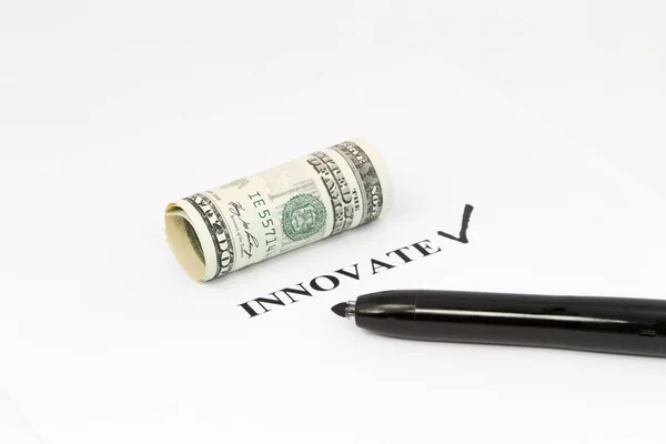 The word, innovate, is printed out with a black check next to it and rolled US currency above.  Black felt tip pen is on the right