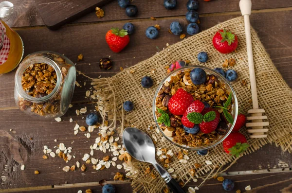 Yogurt with baked granola and berries in small glass, strawberries, blueberries. Granola baked with nuts and honey for little sweetness. Homemade yogurt