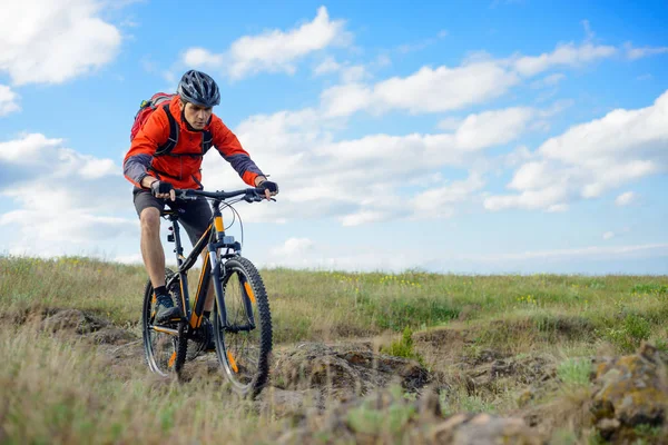 Cyclist in Red Jacket Riding the Mountain Bike on the Beautiful Spring Rocky Trail. Extreme Sport Concept