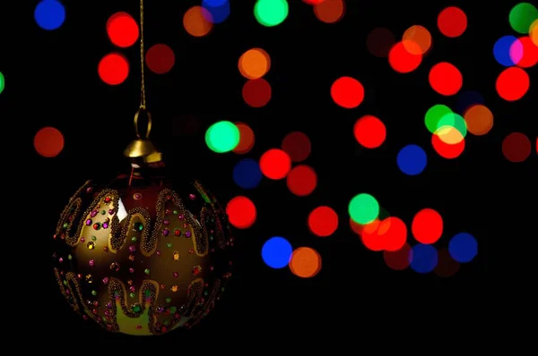 Bauble Natal Ornamentado Pendurado Contra Fundo Preto Com Luzes Coloridas — Fotografia de Stock