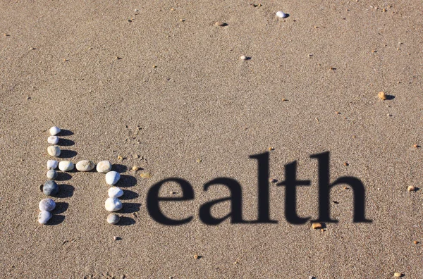 모래에 자갈에 소문자 그림자 텍스트가 추가되어 건강이라는 단어가 스펠트됩니다 — 스톡 사진