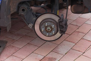 Disk brake on a car here Mechanic at the car brake repair in a car service workshop clipart