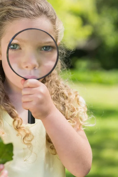 公園で虫眼鏡を通して見ているかわいい少女のクローズアップ肖像画 — ストック写真