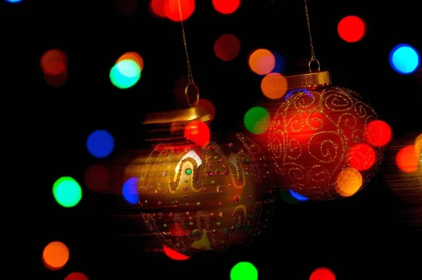 Bauble Natal Ornamentado Pendurado Contra Fundo Preto Com Luzes Coloridas — Fotografia de Stock