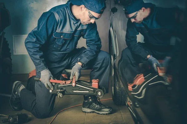 Mechanik Samochodowy Garażu Stara Się Podnieść Samochód — Zdjęcie stockowe