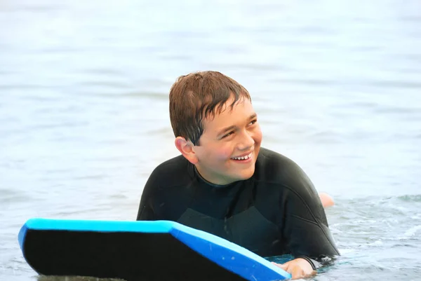 微笑的青少年冲浪者躺在他的身体板上在海洋 — 图库照片