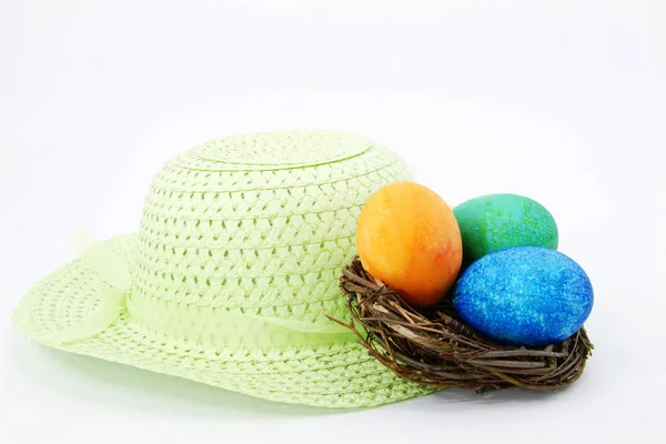 春天绿色的复活节帽子与浅绿色丝带坐在复活节彩蛋染橙色 绿色和蓝色 — 图库照片
