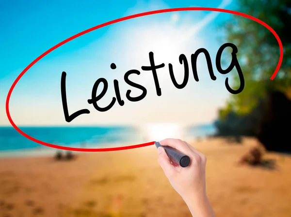 Women Hand writing Leistung (Power in German) with black marker on visual screen. Isolated on beach. Business, technology, internet concept.