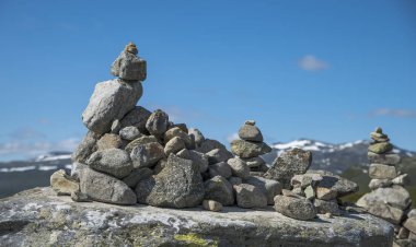 balanced stack of stones at Eidfjorden, Norway with snow and mountains as background clipart