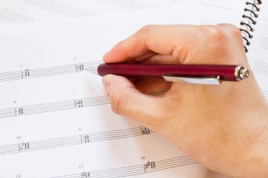 Hand with pen and music sheet, musical background clipart