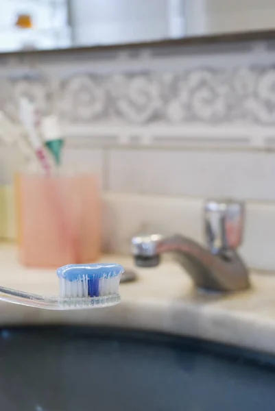 在模糊背景中 带有牙膏的牙刷和盆的详细照片 — 图库照片