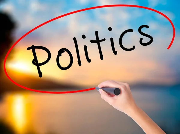 Women Hand writing Politics with black marker on visual screen. Isolated on Sunset. Business, technology, internet concept. Stock Image