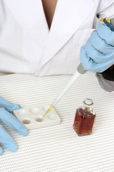 Chemist or scientist using a spotting plate and pipette.  Spot plates are suitable for observing colour or chemical reactions