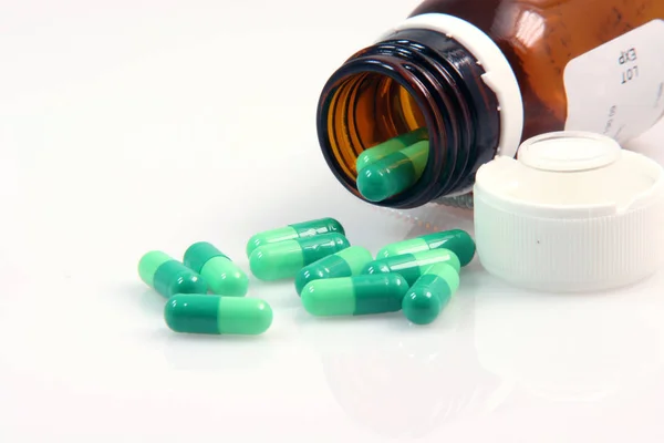 白い背景の医学の概念の緑の丸薬およびガラスのびんクローズアップ — ストック写真