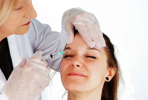 Beautiful young woman getting botox injection to remove wrinkles