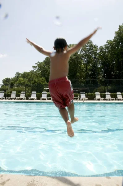 Little boy jumping into pool