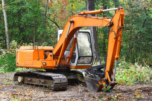 A construction Excavator used forexcavating of trees debris and anything else needed resting on the ground outside in the woods with room for your text.