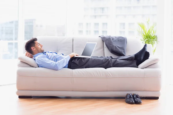 オフィスでラップトップを使ってソファに横たわるビジネスマン — ストック写真