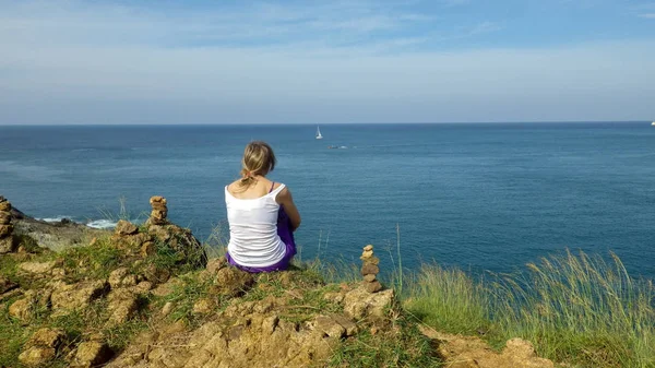年轻女子坐在山上望着大海 在孤独的大海中放松 与自然单独 欣赏海景尺度 — 图库照片