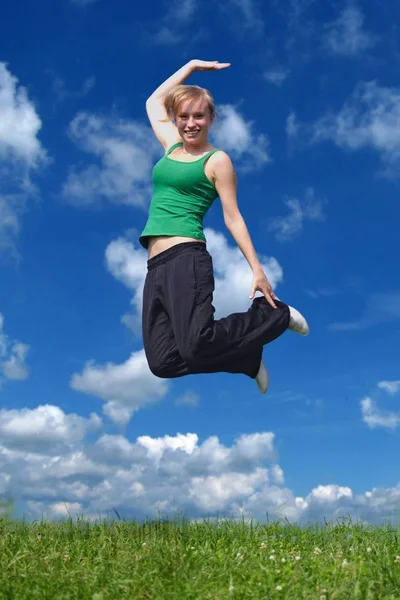 Молодая Привлекательная Женщина Прыгающая Лугу Перед Ярко Голубым Небом — стоковое фото
