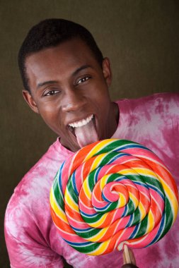 Smiling African-American licks an oversized colorful lollipop clipart
