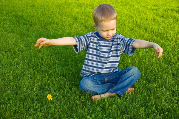 4歳の男の子は草の上に座って足を横切る — ストック写真