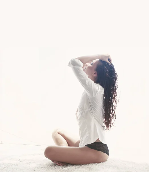 Молодая Женщина Белой Футболке Сидящая Белом Ковре Ярким Утренним Солнцем — стоковое фото