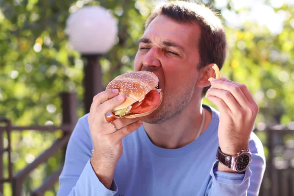 Young man eating burger in fast food