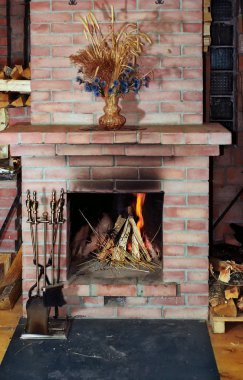 Village fireplace with fire irons and dead flowers on mantelshelf clipart