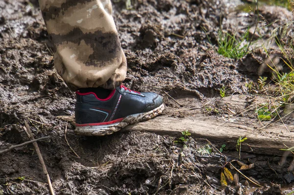 leg tourist in sneakers walks through the mud