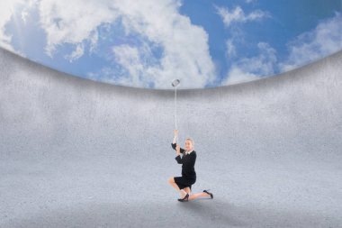 Composite image of businesswoman pulling down blue sky over grey room clipart