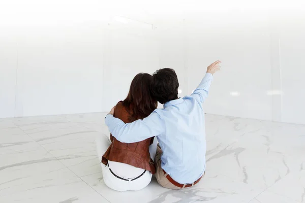 Young Couple Sitting Floor New Empty House Pointing Air — Stock Photo, Image