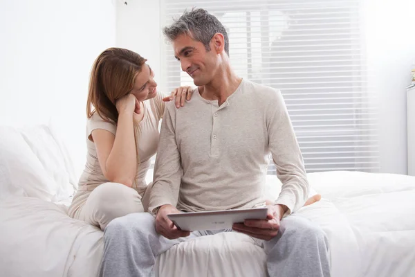 happy couple with digital tablet on bed