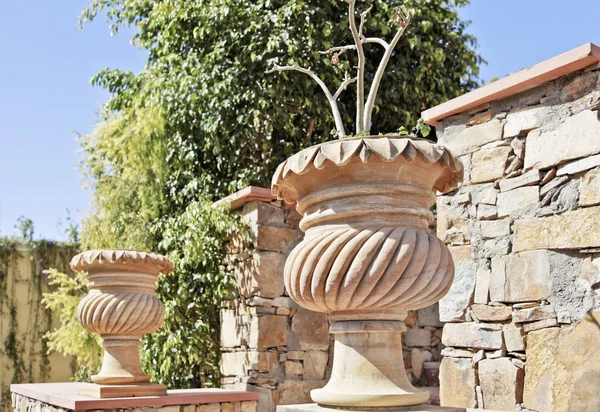 Generic garden featuring stone carved plant pots and random local stone masoned wall. Location of shot Rajasthan, India