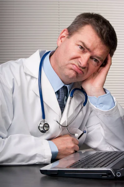 手术台旁的医生靠在手上 看上去既不快乐又无聊 看着远方 — 图库照片
